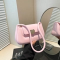 Chic pink crossbody bag with a gold heart clasp for women in a lifestyle interior setting - Pink