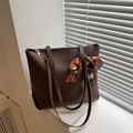 Borsa tote marrone scuro con texture litchi e foulard in seta su piano bianco - Marrone Scuro