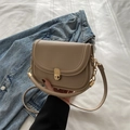 Borsa a sella beige crema in pelle opaca con chiusura dorata su una giacca di jeans - Cachi