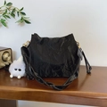 Bolso bucket negro con textura plisada, correa ancha y detalles metálicos dorados - Con Colgante / Negro