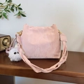 Bolso saco rosa plisado con correa trenzada y colgante de peluche en una mesa - Con Colgante / Rosa