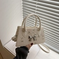 Chic woven trapezoid handbag with floral embroidery and metallic bow charm - White