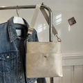 Minimalist creamy white bucket bag with wide strap and gold hardware hanging view - White