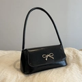 Glossy black patent leather handbag featuring a decorative gold metal bow on the front - Black
