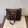 Dark brown crocodile pattern shoulder bag with a gold bow metal accent on a book - Brown