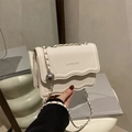 White faux leather crossbody bag with wavy edge flap and silver metal chain strap - White