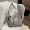 Minimalist beige leather crescent underarm bag with adjustable strap on white chair - Khaki
