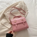 Pink vintage messenger bag with top handle and golden hardware on a beige background - Pink