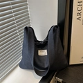 Minimalist deep blue denim tote bag with fashion label shown in a lifestyle setting - Blue