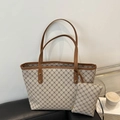 Beige monogram tote bag set with brown leather straps on a stylish black sofa - Gray