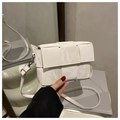 Close-up of cream woven square crossbody bag with textured marble finish and silver clasp - White