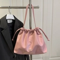 Pink pleated drawstring shoulder bag with silver bow accent on dark blazer backdrop - Pink