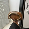 Brown leather crossbody bag with golden C-handle and snake chain strap in hand - Brown