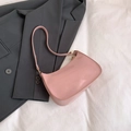Minimalist light pink patent leather underarm bag with gold accents on a grey blazer - Pink