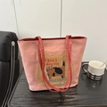 Sac fourre-tout rose style preppy avec broderie chat et bandoulières rouges sur table - Rose