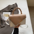 Minimalist beige crossbody bag with camel flap and woven handle in lifestyle setting - Khaki