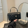 Elegante schwarze Stepphandtasche mit goldener Blume und Kettenriemen auf Schminktisch - Schwarz