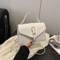 White faux leather crossbody bag with golden buckle and adjustable strap in hand - White