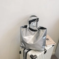 Metallic silver tote bag with adjustable straps placed on a white suitcase - Silver