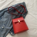 Retro red faux leather bucket bag with gold clasp shown on a blue denim jacket - Red