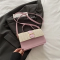 Roze en beige geweven crossbodytas met goudkleurige gesp op een grijze blazer achtergrond - Roze