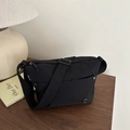 Borsa a tracolla minimalista in nylon nero con tracolla regolabile su tavolo in legno - Nero