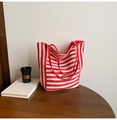 Détail du sac cabas en toile rayée rouge et blanc avec logo ovale en bronze sur table - Rouge Double Face