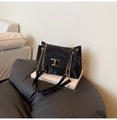Close-up of black pleated tote bag featuring gold T-buckle and elegant chain strap - Black