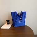 Blue nylon tote bag with minimalist logo print on wood table for daily use - Blue Side B (Letter Print)