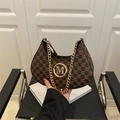 Brown monogram hobo bag with gold M-logo and chunky chain strap on a black chair - Brown