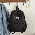 Minimalistischer schwarzer Rucksack mit Smiley-Patch hängend an einem Holzhaken - Schwarz