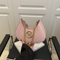 Pink semi-circle baguette bag with gold metal M logo and chain strap on a white magazine - Pink