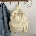Minimalistischer cremefarbener Nylonrucksack mit Smiley-Patch an einem Wandhaken aus Holz - Gelb