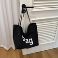 Borsa tote in tela nera con scritta bag appesa alla maniglia di una porta - Nero