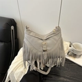 Grey suede tote bag with long bohemian fringe and golden buckle on dark leather sofa - Gray