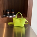 Neon green litchi leather bucket bag with gold hardware on a metallic surface - Green