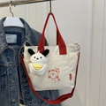 White canvas tote bag with red straps featuring a cartoon bear and plush puppy charm - With Ornament / Red