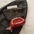 Red patent leather pillow bag with gold U-handle and chain strap on dark blazer - Red