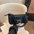 Elegante schwarze PU-Schultertasche mit goldener Schleife und Knotengurt auf modernem Stuhl - Schwarz