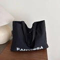 Minimalistische schwarze Einkaufstasche mit weißem FANYISSA-Logo auf Holztisch - Schwarz