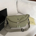 Close-up of green nylon crescent crossbody bag with double zippers and metallic logo detail - Green