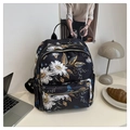 Close-up of black backpack with white daisy floral prints and gold metal zippers - Flower
