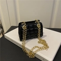 Schicke schwarze gesteppte Mini-Umhängetasche mit goldener Kette auf weißem Buchhintergrund - Schwarz