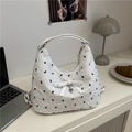White textured shoulder bag with black letter print and elegant bow detail on a desk - White