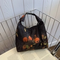 Black nylon tote bag featuring vibrant orange persimmon prints and buckle detail - Good Luck/Everything Goes Well