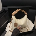 Bolso saco crema con textura plisada y asa trenzada marrón sostenido en mano - Blanco Roto