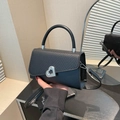 Classic black crossbody bag with silver heart buckle and dual-texture leather design - Black
