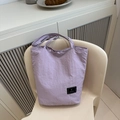 Detailed view of light purple nylon tote bag featuring a black woven brand label - Purple