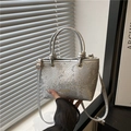 Silberne Handtasche mit Schlangenprägung und goldenem Logo in minimalistischem Licht - Silber