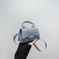 Close-up of light blue mini handbag featuring woven texture and knot detail on flap - Blue